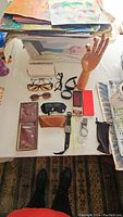 Overview of entire lot on table showing eyewear, watches, wallets, and model hand