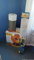 Photo showing Presto HeatDish heater box with orange heater image, Blueair model 411 cylindrical air purifier, and Hi Reach cleaning kit box.
