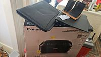 Canon all-in-one printer in box with some office organizer items on top