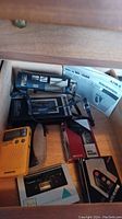 Photo showing several cassette players and a yellow portable transistor radio in a wooden drawer, includes Aiwa manuals.