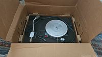 Overview of turntable in original box showing plinth, platter and cables