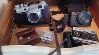 Three cameras on wooden surface with cases and accessories