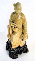 Front view of Chinese soapstone carving showing figure seated with basket and black base