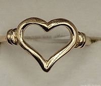 Close-up of gold open heart ring showing heart shape, band, and details.