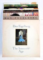 Photo of 10 vinyl LP records stacked vertically showing cover art of Dan Fogelberg's The Innocent Age and visible album spines.