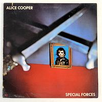 Front cover of Alice Cooper 'Special Forces' album showing small portrait frame on a blue and red abstract background with metallic elements.