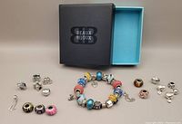 Photo showing entire set of Pandora-style bracelet and loose beads with Beaux Bijoux box in background.