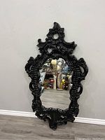 Full view of large black vintage-inspired ornate framed mirror hanging on wall