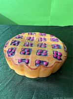Top view of the candle showing the lattice pie crust design with dark red berry details.