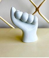 Front view of the white ceramic hand-shaped vase showing the thumb extended and smooth glossy surface.