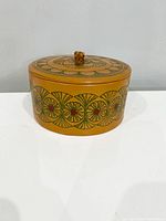 Front angle showing rounded floral patterned faux leather jewellery box with lid and knob handle.