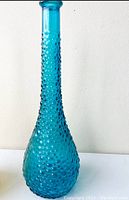 Photo of blue hobnail glass genie bottle decanter, showing tall narrow neck and bulbous textured base.
