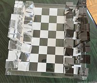 Chess set arranged on lucite chess board on table, showing full set of clear and smoky acrylic chess pieces