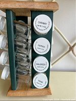 Close-up side view of four labeled spice jars in rotating rack: Caraway, Paprika, Fenugreek, Thyme.