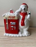 Front view of the ceramic cookie jar showing the polar bear with Santa hat and vending machine side