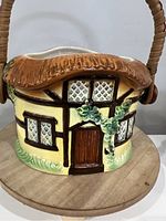 Front view of the ceramic biscuit barrel shaped like a thatched cottage with detailed door, windows, and ivy decoration.
