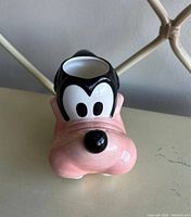 Front view of the ceramic mug shaped like Goofy's head, showing black hair, large white eyes, and pink snout.