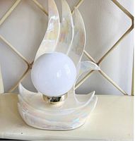 Full front view of unlit lamp showing sculptural flame shape and iridescent finish