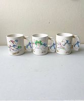 Set of three vintage ceramic mugs with colorful goose illustrations and white goose-shaped handles viewed from the front.