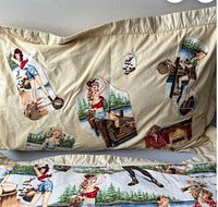Photo shows two cream-colored pillowcases with various vintage pin-up girls in outdoors cabin scenes printed on fabric.