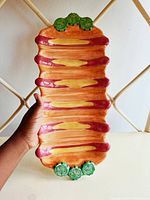 Top view of platter showcasing detailed hotdog and pickle decoration in ceramic glaze.