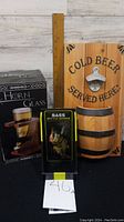 View of all three items together: wooden bottle opener plaque, boxed horn glass, and Bass fish bottle opener