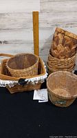 Seven different decorative baskets shown including the large rectangular basket with lace trim and handles, and a few round woven baskets.