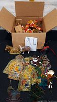 Wide view capturing the box of bears and assorted decorative items including plastic stained glass style hangings and animal figurines