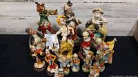 Photo of 15 assorted clown figurines in varied poses and colors.