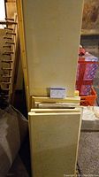 Set of 15 yellow shelving boards stacked against a wall, showing various sizes.