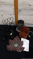 Photo showing black metal heart-shaped votive holders, leaf-shaped brown metal holder, silver perforated tin holder, and rusty square holder with cutouts.