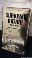 Front view of the metal survival ration box showing the label 'SURVIVAL RATION CRACKERS' and net weight 5 1/2 pounds.