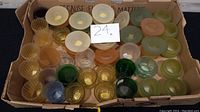 Photo of over 50 assorted glass votive and tea light candle holders in a box with mixed colors including clear, amber, green, and frosted.