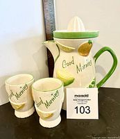 Front view of juice set showing jug with green handle and two cups with 'Good Morning' text and citrus decorations