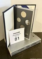 View of the open presentation folder with six Canadian coins from 1992 mounted in a transparent plastic holder inside a black folder, box visible below.