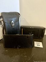 Photo showing the antique Kodak folding camera and original black leather case with shoulder strap.