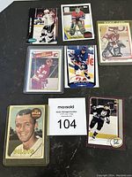 Photo of seven hockey and baseball cards showing close view of players Wayne Gretzky, Patrick Roy, Joe Nieuwendyk, Felix Potvin, and Al Oyler. Some cards in sleeves.