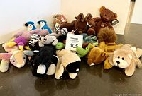 Wide view of the lot showing the entire collection of plush animals including bears, birds, skunk, dolphin, zebra and others with their Ty Beanie Baby tags visible
