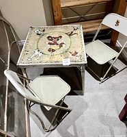 Photo showing vintage child's square table with Punkinhead illustration and two matching chairs placed around it.