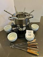 Full view of complete fondue set including pot on stand with burner, forks, and bowls.