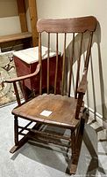 Front view of old wooden rocking chair showing seat, armrests, and spindle back.