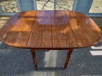 Top-down view of fully extended dining table showing roll out extension and drop leaves.