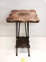 Front view of antique wooden plant stand showing scalloped top surface with weathered finish and ball feet.