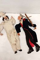 Two full-length handcrafted marionette puppets lying side by side showing overall condition and outfits.