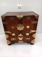 Front view of wooden cabinet showing two doors, one drawer and brass hardware