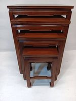 Front view of all four wooden nesting tables stacked inside each other.