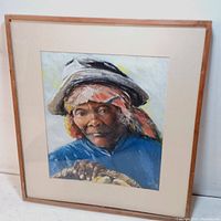 Framed pastel portrait of an elderly woman wearing a hat and scarf, showing overall artwork and framing.