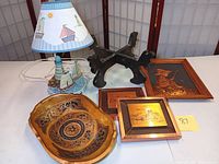 Overview of ceramic sailboat lamp, Asian planter stand, copper wall art piece, two framed copper plaques, and lacquered wood bowl on white background.