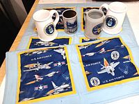 Four items displayed on the Air Force quilt: two Air Force themed ceramic steins, one ceramic cup with scenic design, and the Air Force quilt itself.