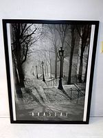 Framed black and white poster depicting a Parisian stairway with street lamps and bare trees in a moody atmosphere.